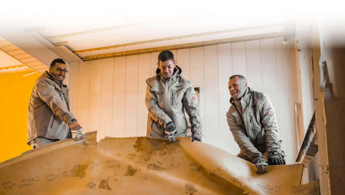 Drei Männer reißen Teppich bei professioneller Entkernung durch Dienstleistungen Mazreku heraus. Entkernungen.